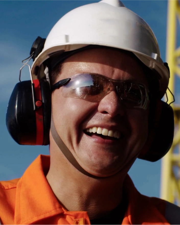 Um homem usando óculos de segurança e capacete sorrindo para a foto