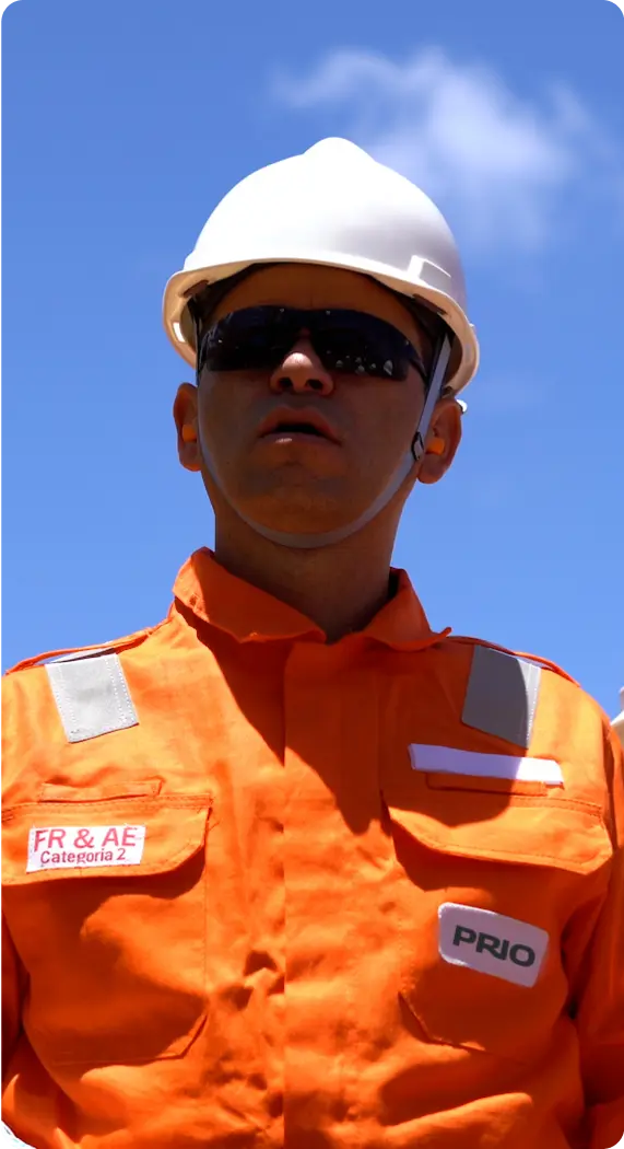 Um homem usando capacete branco, óculos escuros e macacão laranja